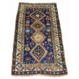 A Kazak rug, mid 20th Century, with four lozenge medallions in deep blue field, with ivory main