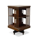 An Edwardian mahogany and marquetry inlaid revolving bookcase, the square top centred by dolphin and