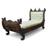 An Italian carved walnut day bed, late 19th Century, the curved headboard surmount with finials