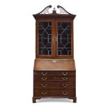 A George II mahogany bureau bookcase, with pierced and fret carved swan neck pediment, centred by