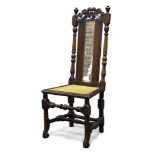 A stained beech and caned highback chair, 17th Century and later, the top rail with carved and
