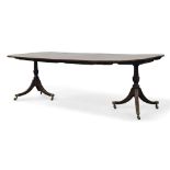 A George III twin pedestal dining table, the rounded rectangular top with two additional leaves,