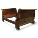 A Charles X mahogany lit en bateau, with scroll end headboard and footboard, raised on later