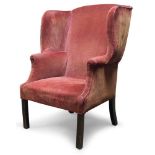 A George III wingback armchair, with serpentine wings, upholstered in red velvet, raised on square