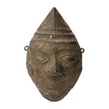 A bronze mask, Kerala, India, 19th century, with delineated almond eyes, arched eyebrows, pointed