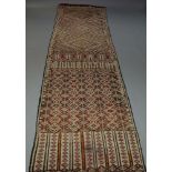 WITHDRAWN. A Caucasian woven wool work runner, with polychrome lozenge design, 550cm x 118cm,
