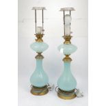A pair of continental opaline glass table lamps, 20th century, the compressed reservoir above