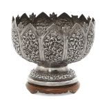 An Indian silver bowl, raised on a wooden stand to a circular foot, the body chased with elaborate