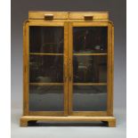 An Art Deco oak bookcase, the raised top with two frieze drawers, above two glazed cupboard doors,