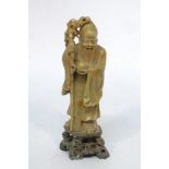 A Chinese soapstone figure of Shou Lao, early 20th century, carved holding a peach and an ancient