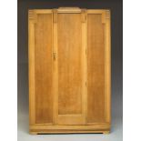 An Art Deco oak wardrobe, with floral and geometric moulding to top, having central cupboard door