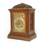An Edwardian carved oak mantle clock, with domed and pyramid form top applied with foliate