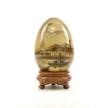 A Russian wood painted souvenir egg, decorated with a scene of a steam boat in front of a