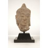 A Khamer style carved stone head of Buddha, early 20th century, 27cm high on a black painted