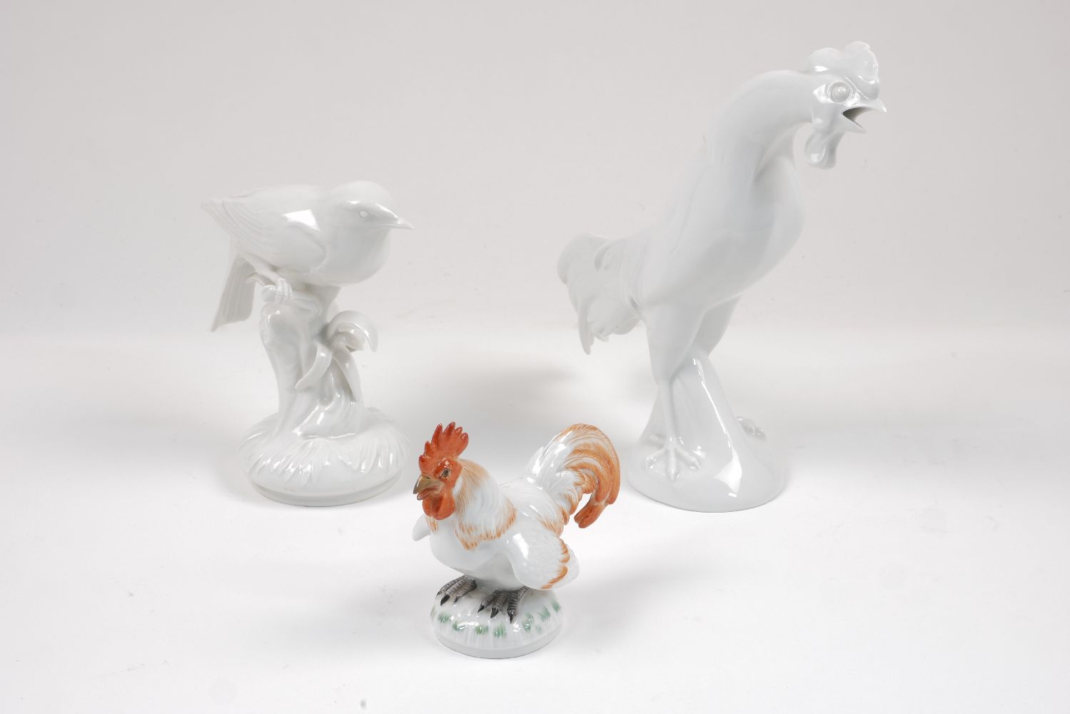 A Meissen figure of a cockerel, 20th century, decorated with red glazes, standing on a round base,