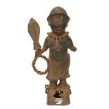 A Benin style bronze figure of a Chieftain, modelled standing holding a ceremonial paddle and quoit,