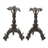 A pair of Chinese bronze tripod candlesticks, Ming dynasty, each raised on three leags cast as a