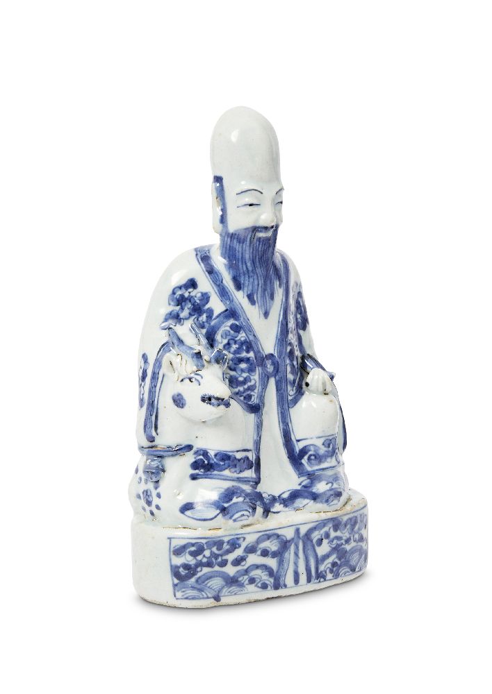 A Chinese porcelain figure of Shoulao, Ming dynasty, Wanli period, modelled seated on a recumbent