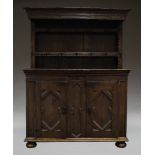An oak dresser, 18th Century and later, the plate rack with two shelves, each with a series of pegs,