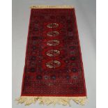 A Tekke rug, with five guls in a deep red field, 137cm x 68cm, together with a Caucasian rug, with