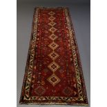 A Kazak runner, late 20th Century, with nine lozenge medallions in deep red field, with ivory main