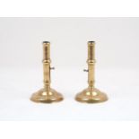 A pair of English brass pusher candlesticks, 18th century, each of typical plain polished form, with