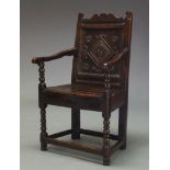 An oak Wainscot Armchair, 17th Century, the shaped crest rail above panelled back, carved with