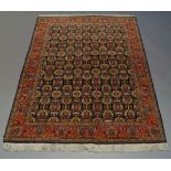 A Qum rug, late 20th Century, with repeat vase and floral spray pattern in indigo field, with red