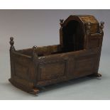 An oak rocking cot, late 17th, early 18th century, with hood and turned finials, above paneled