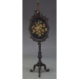 A Victorian mahogany fire screen, the oval frame with scrolling foliate decoration centred by carved