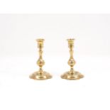 A pair of English brass candlesticks, 18th century, with spool-shaped sockets and flared rims, to