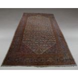 A large West Persian carpet, with repeat flowerhead design in ivory field and indigo main border,