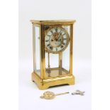 An early 20th century brass framed four-glass clock, the white enamel dial with black roman