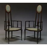 A pair of Edwardian mahogany highback armchairs, the backrest with oval upholstered panels above