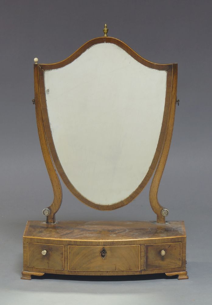 A George III mahogany and boxwood strung toilet mirror, the shield shaped plate above a three drawer