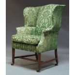 A George III style wing back armchair, 20th Century, with green floral pattern upholstery and one