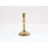 A brass candlestick, late 17th century, designed with hexagonal sided socket, wax ejecting hole,