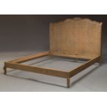 A limed wood and caned bed, of recent manufacture, the caned head board with carved floral