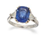 A sapphire and diamond three stone ring, the cushion shaped sapphire centre between triangular-cut