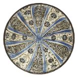 A blue black and white Kashan pottery bowl, Iran, circa 1220, of conical shape on a short foot, frit