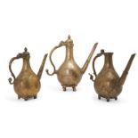 Three Mughal engraved brass ewers, 18th century India, each of pear shape on four feet, with