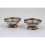 A pair of hammered white metal candlestick holders, of stepped, circular form, each raised on a