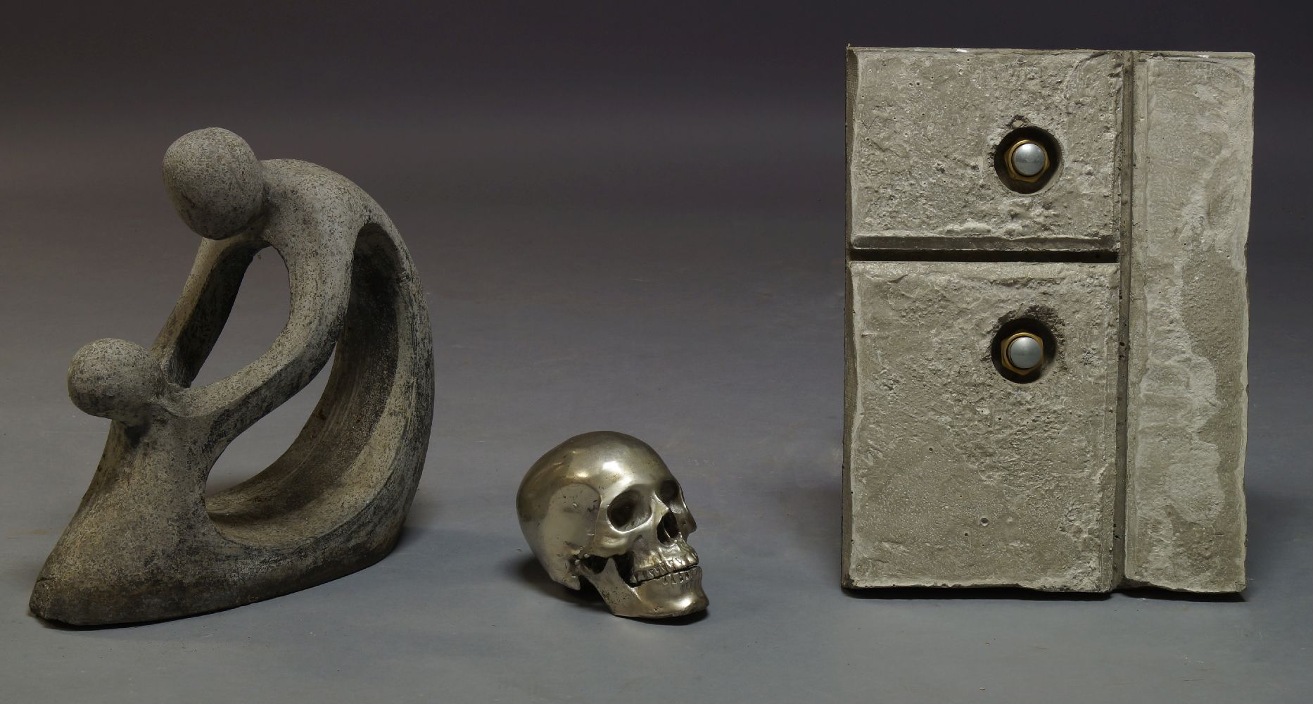 A cast white metal skull, 20th Century, together with a contemporary composite stone figural