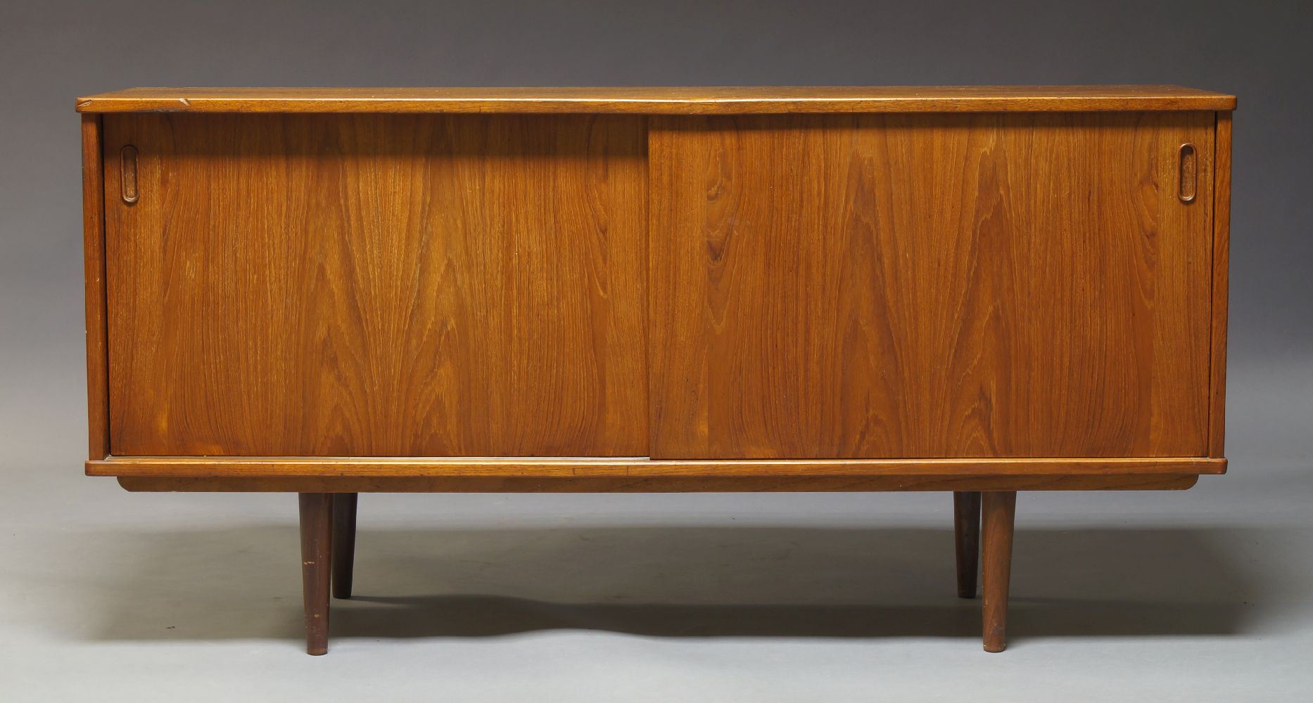 Dyrlund, a teak sideboard, c.1960, with two sliding doors enclosing storage space, a drawer and