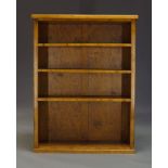 A satinwood freestanding open bookcase, mid 20th Century, with three adjustable shelves, raised on