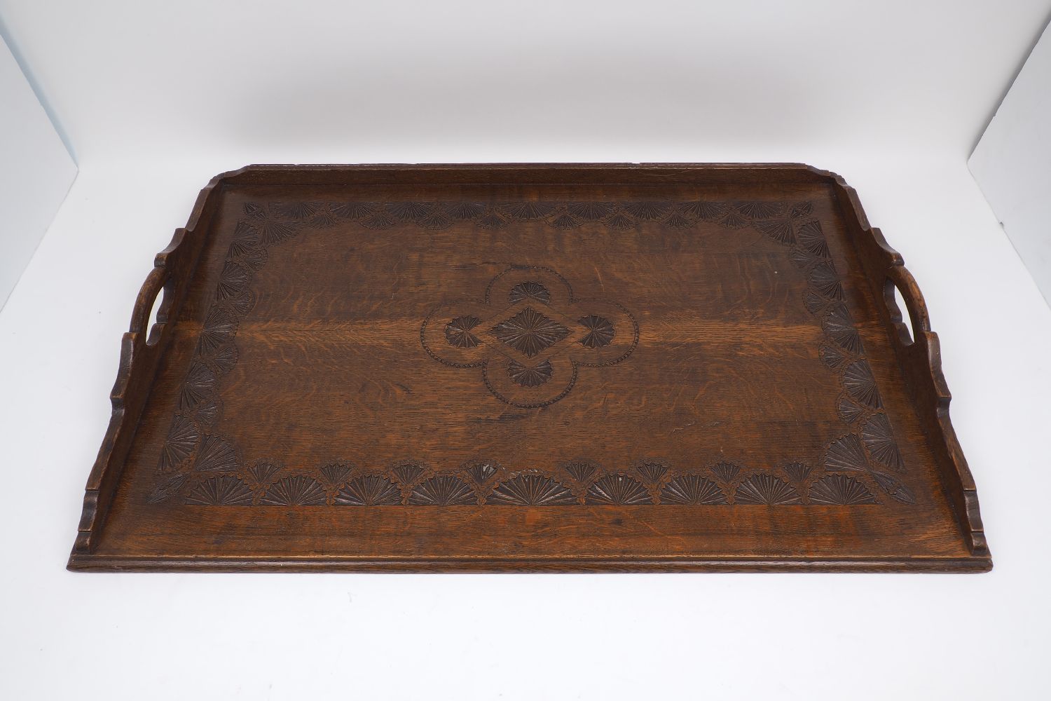 An oak Arts and Crafts style tray, with stepped handle design to either side, the tray bearing a