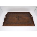 An oak Arts and Crafts style tray, with stepped handle design to either side, the tray bearing a