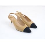 A pair of Chanel sling-back heeled pumps, designed in beige and black, with adjustable buckle