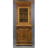 A late Victorian carved oak bookcase cabinet, the moulded cornice above gadrooned frieze, flanked by