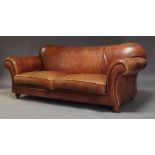 A tan leather two seat sofa, late 20th Century, with two loose seat cushions, raised on turned feet,